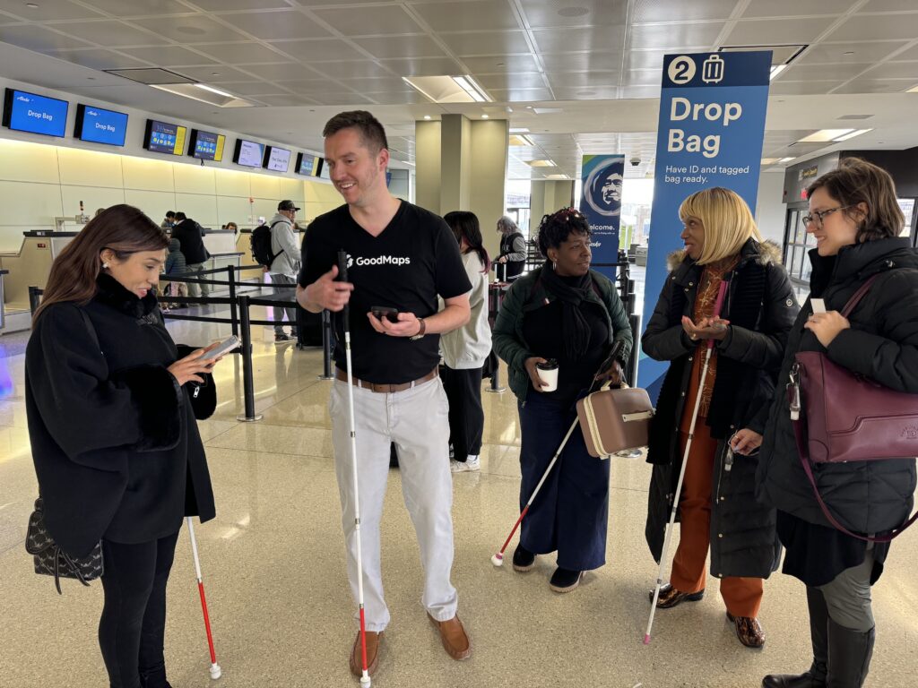 Kevin stands with a group of users who are holding their smartphones and canes.