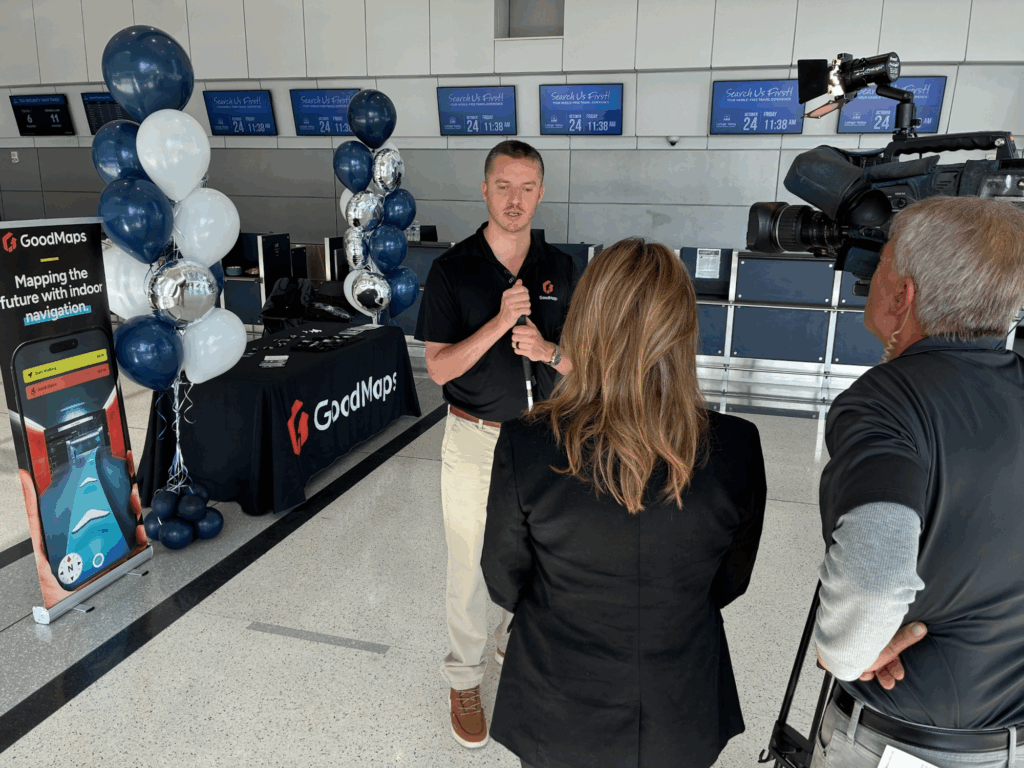Kevin Kline is being interviewed on camera in Lehigh’' terminal next to a GoodMaps promotional table and a display of balloons. The GoodMaps banner promotes indoor navigation technology.