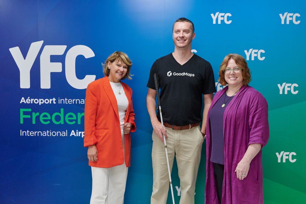 Kevin poses with two members of the YFC team against a green-and-blue backdrop.