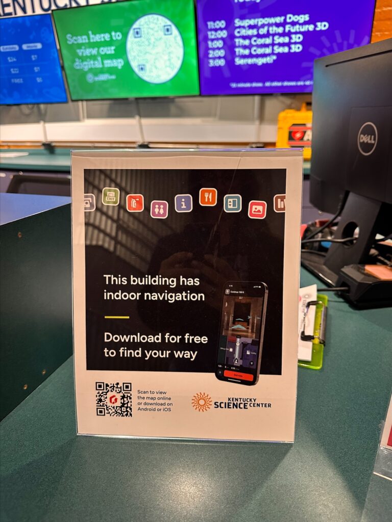 Counter sign at Kentucky Science Center advertising GoodMaps' free indoor navigation app with QR code to download the digital building map.