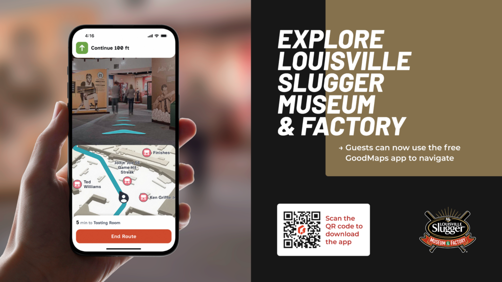Hand holding a smartphone showing indoor navigation in the Louisville Slugger Museum & Factory, with on‑screen map and arrows, alongside text promoting the GoodMaps app and QR code to download it.